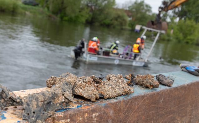 Slide Fragmente von Kampfmitteln am Schiff. Im Hintergrund verrichten die Taucher den gefährlichen Job.