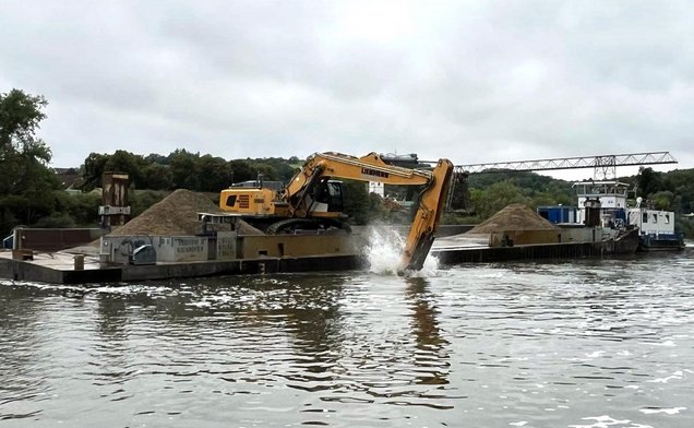 Slide Ein Bagger hebt Sedimente aus dem Wasser